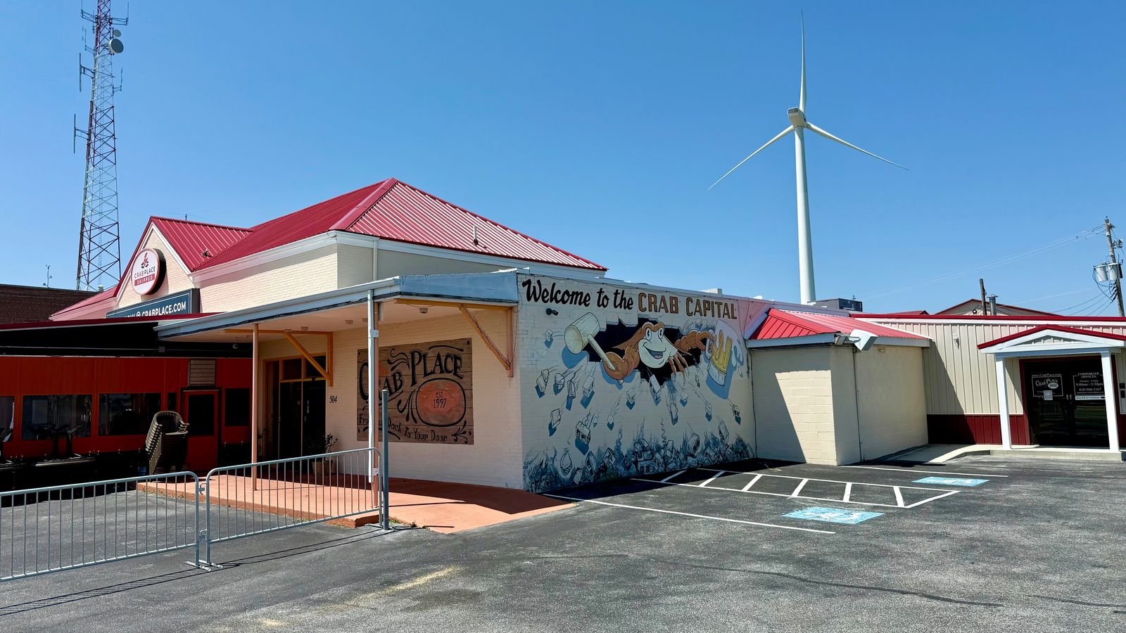 The Crab Place facility in Crisfield with its red roof, Crab Place signage, and the Welcome to the Crab Capital mural